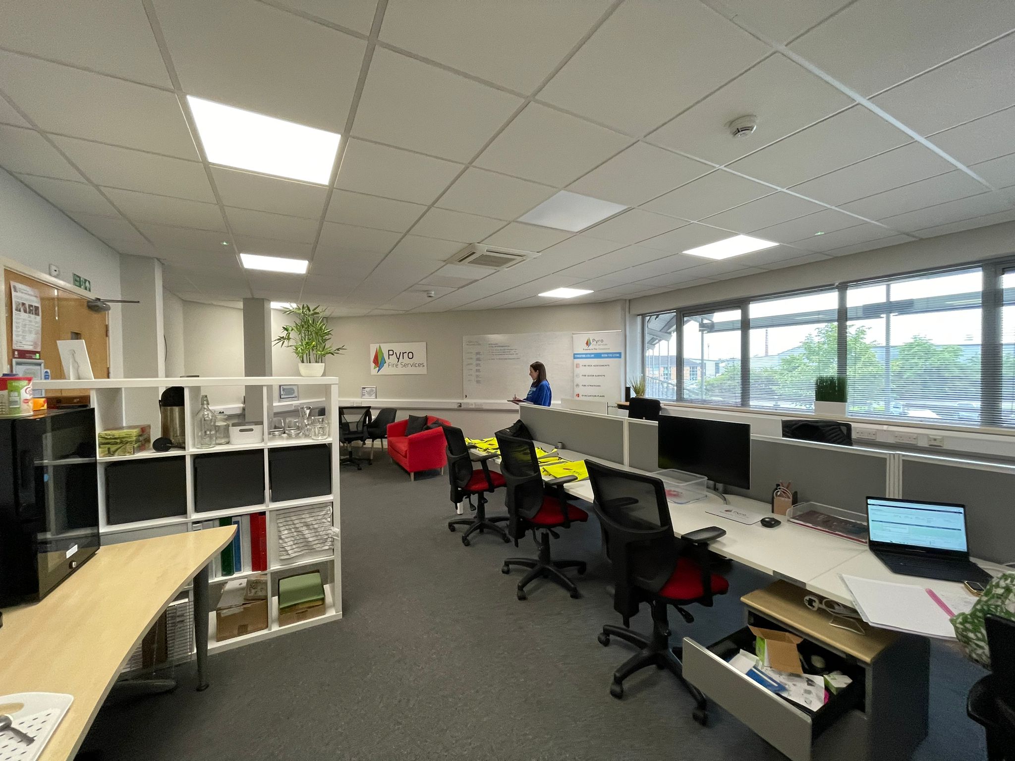 The Pyro Fire open plan office before the redesign, with rows of desks, red task chairs and open storage shelving