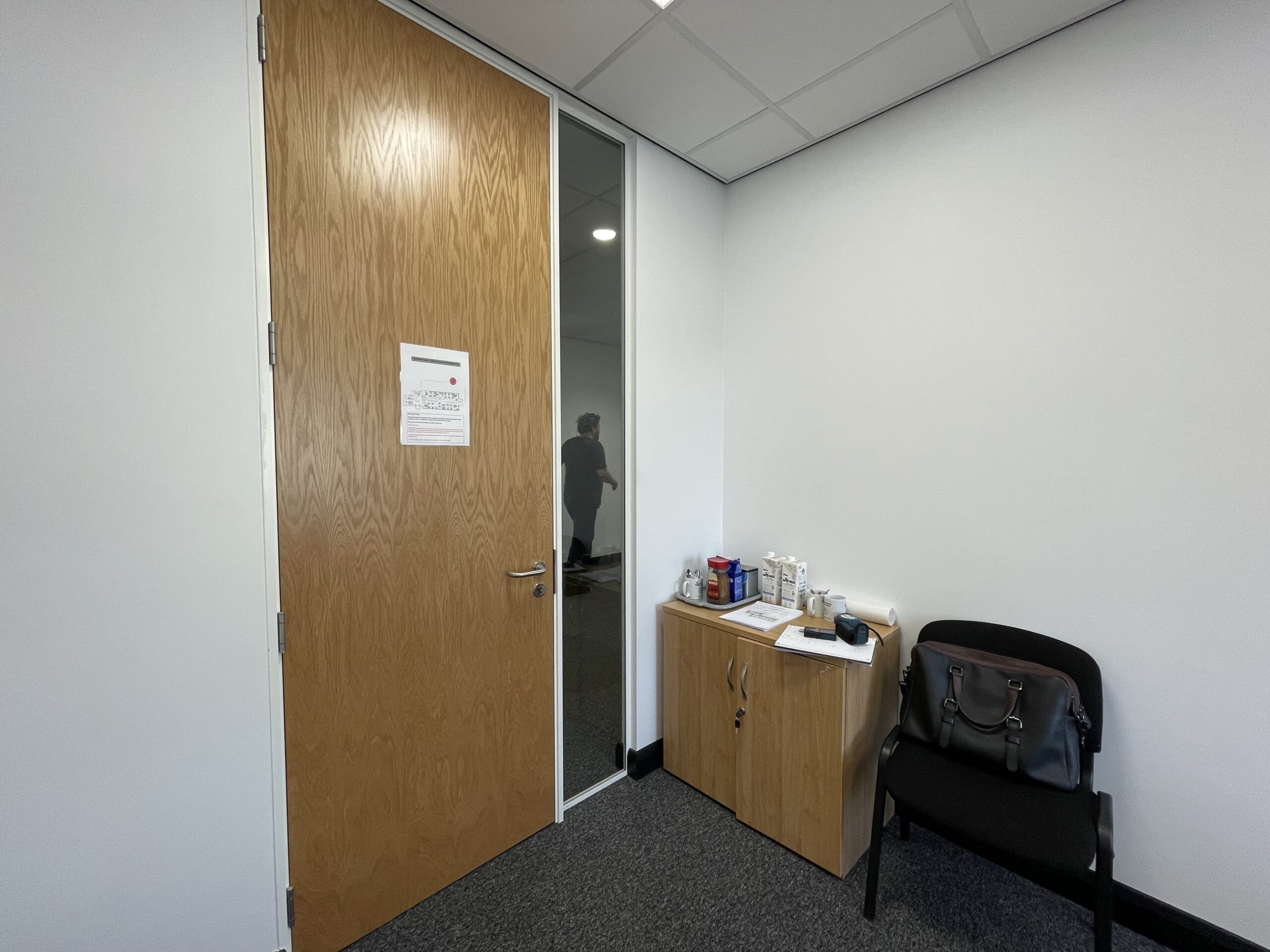 A corridor at Doncaster Chamber before the refresh, with a timber door and a low cupboard against a bare wall