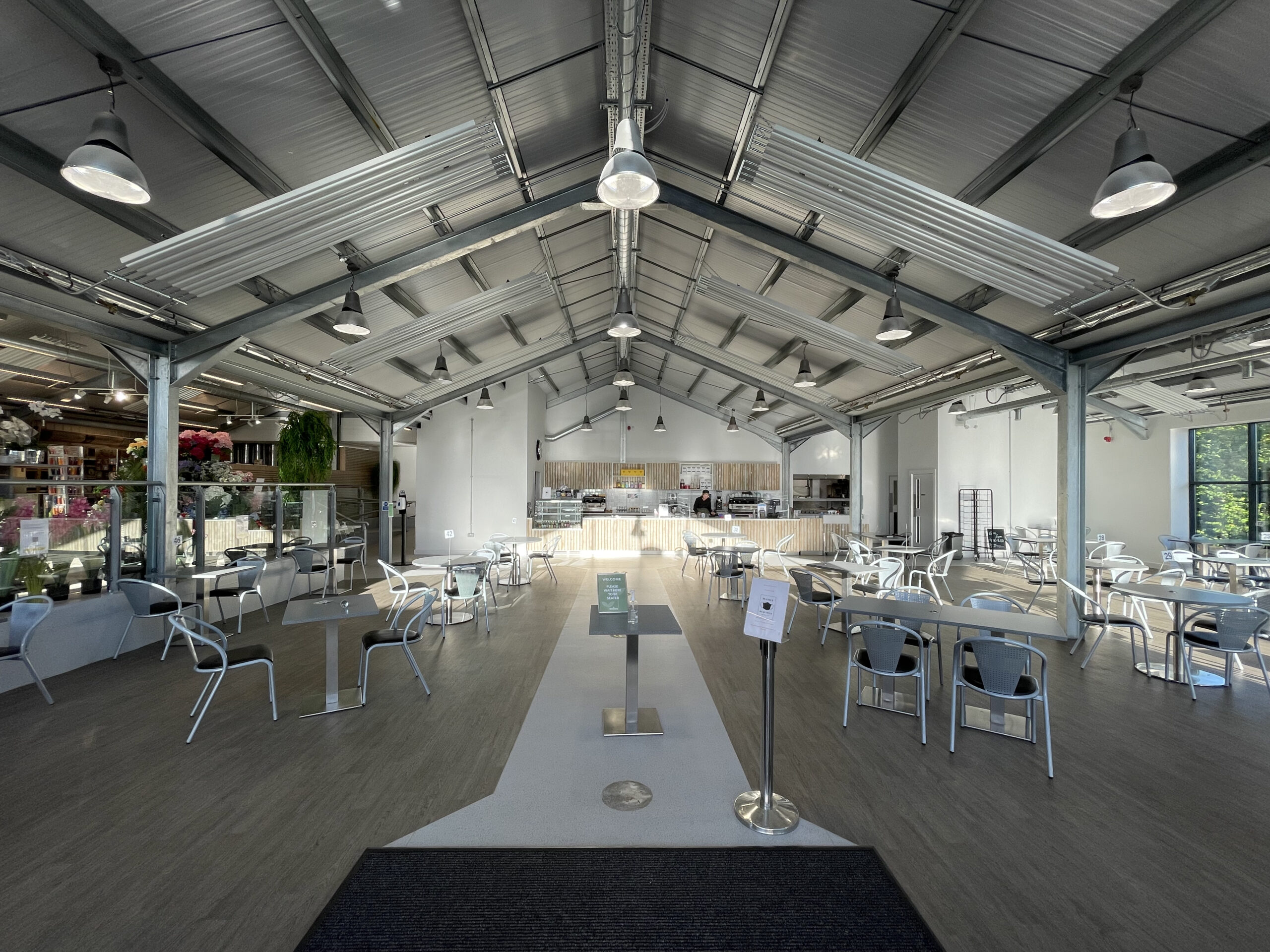 The New Shoots garden centre cafe before the redesign, a wide room of loose tables and metal chairs under a pitched roof