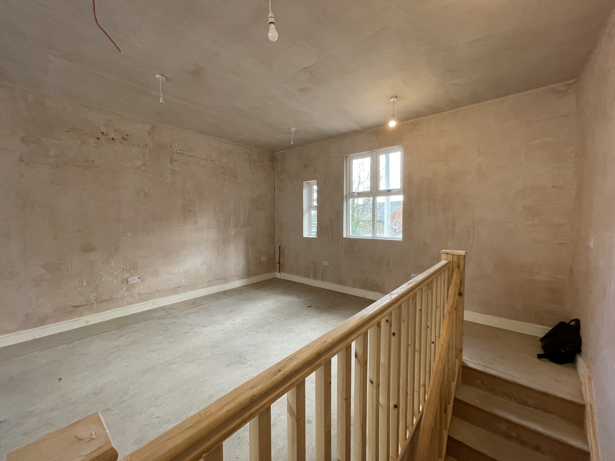The Burrito Picante unit before the fit out: bare plastered walls and a timber balustrade around a new mezzanine