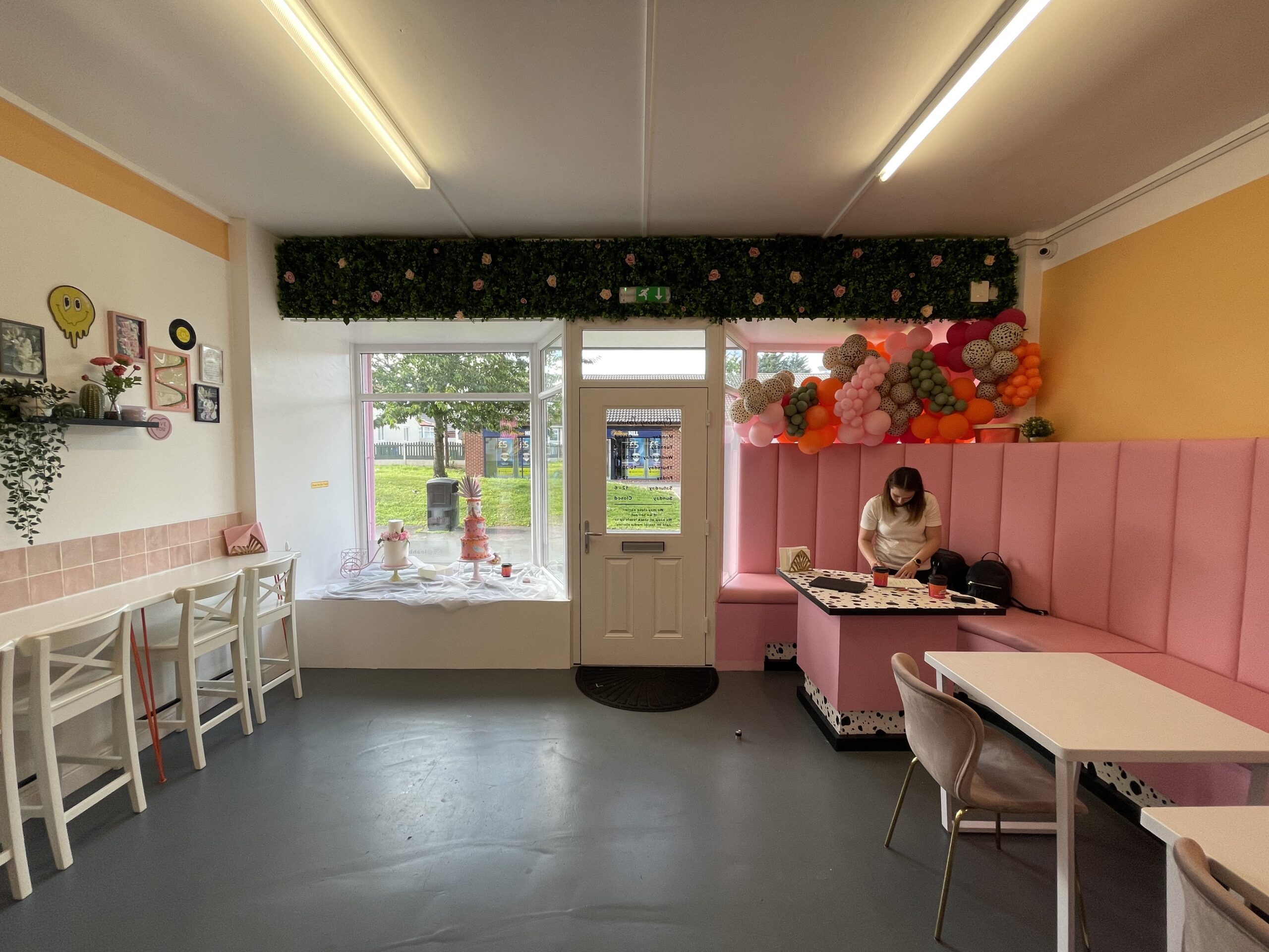 The bakery seating area before the redesign, with a pink banquette, high stools and a window onto the street
