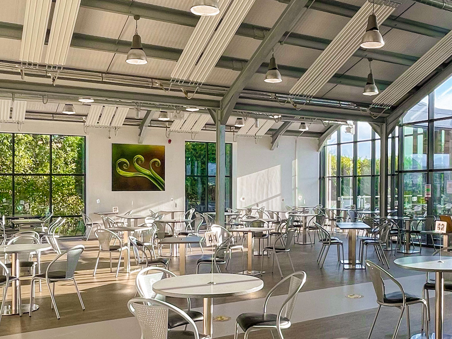 The New Shoots cafe before the redesign, a large glazed room filled with metal chairs and cafe tables