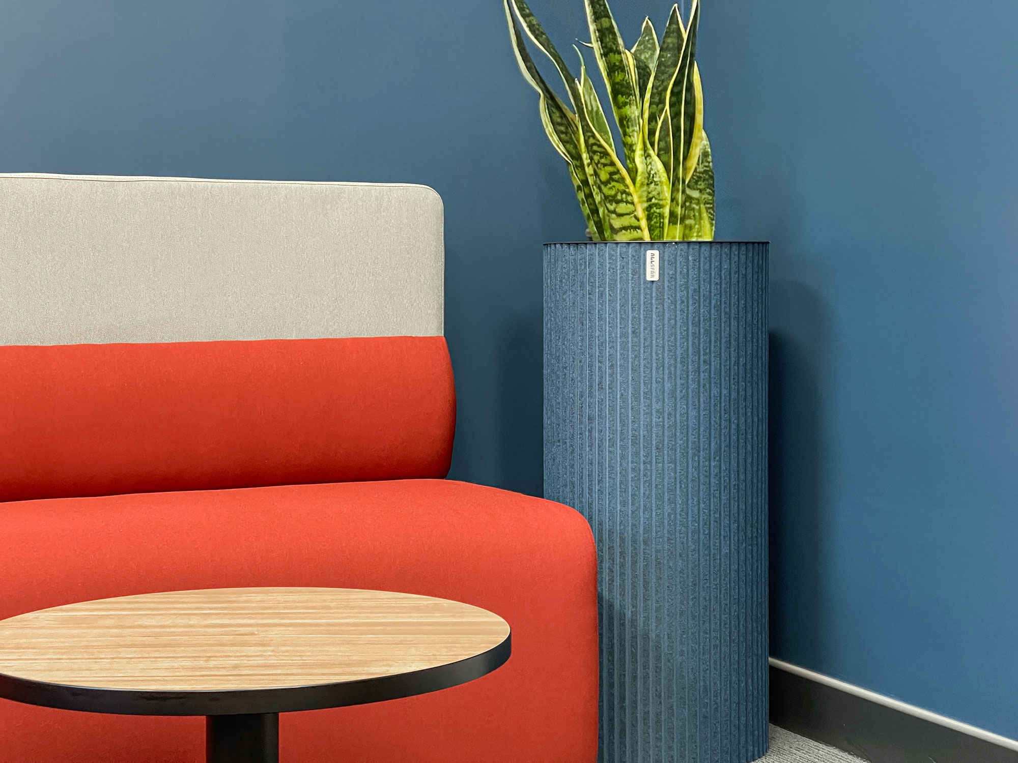 Soft seating in red and cream with a round timber table, set against a blue wall in a school