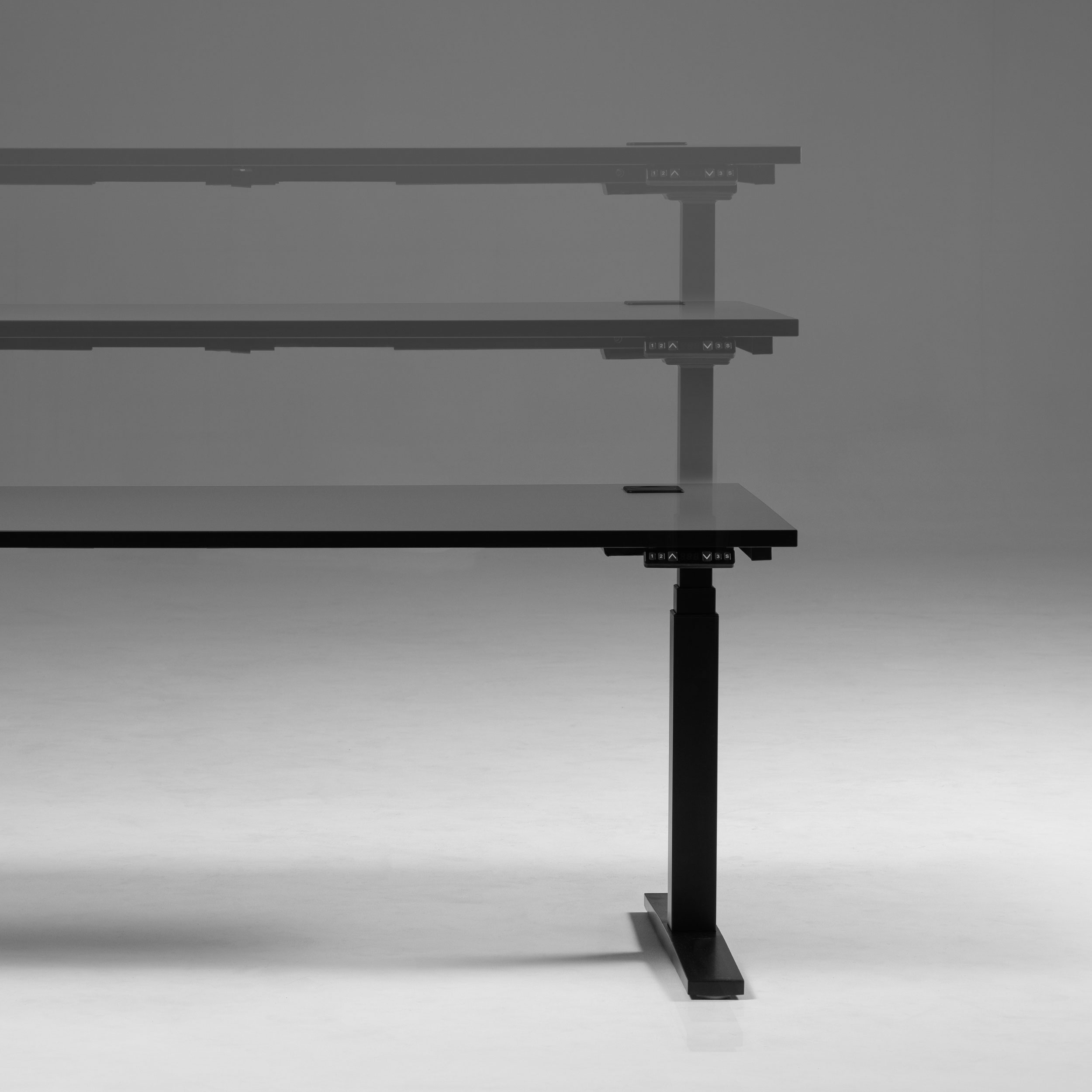 A height adjustable desk with a black frame, photographed against a plain background