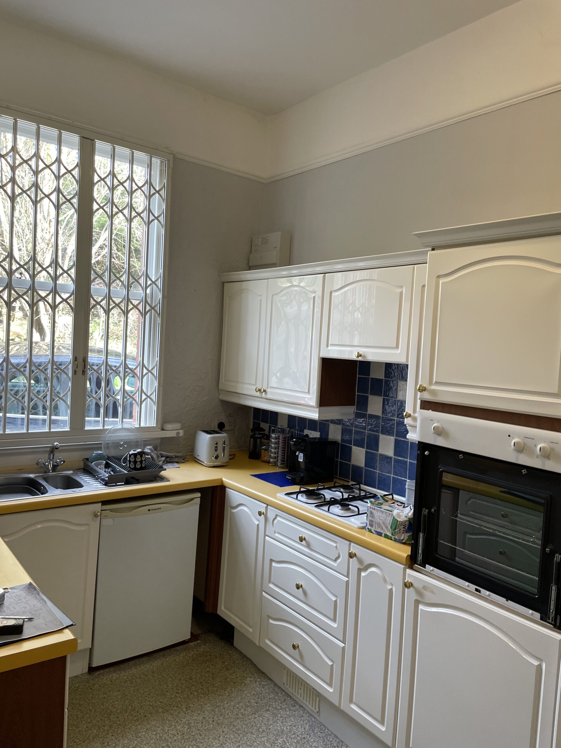 The kitchen at Aspire PC before the redesign, with dated cream units and blue tiles