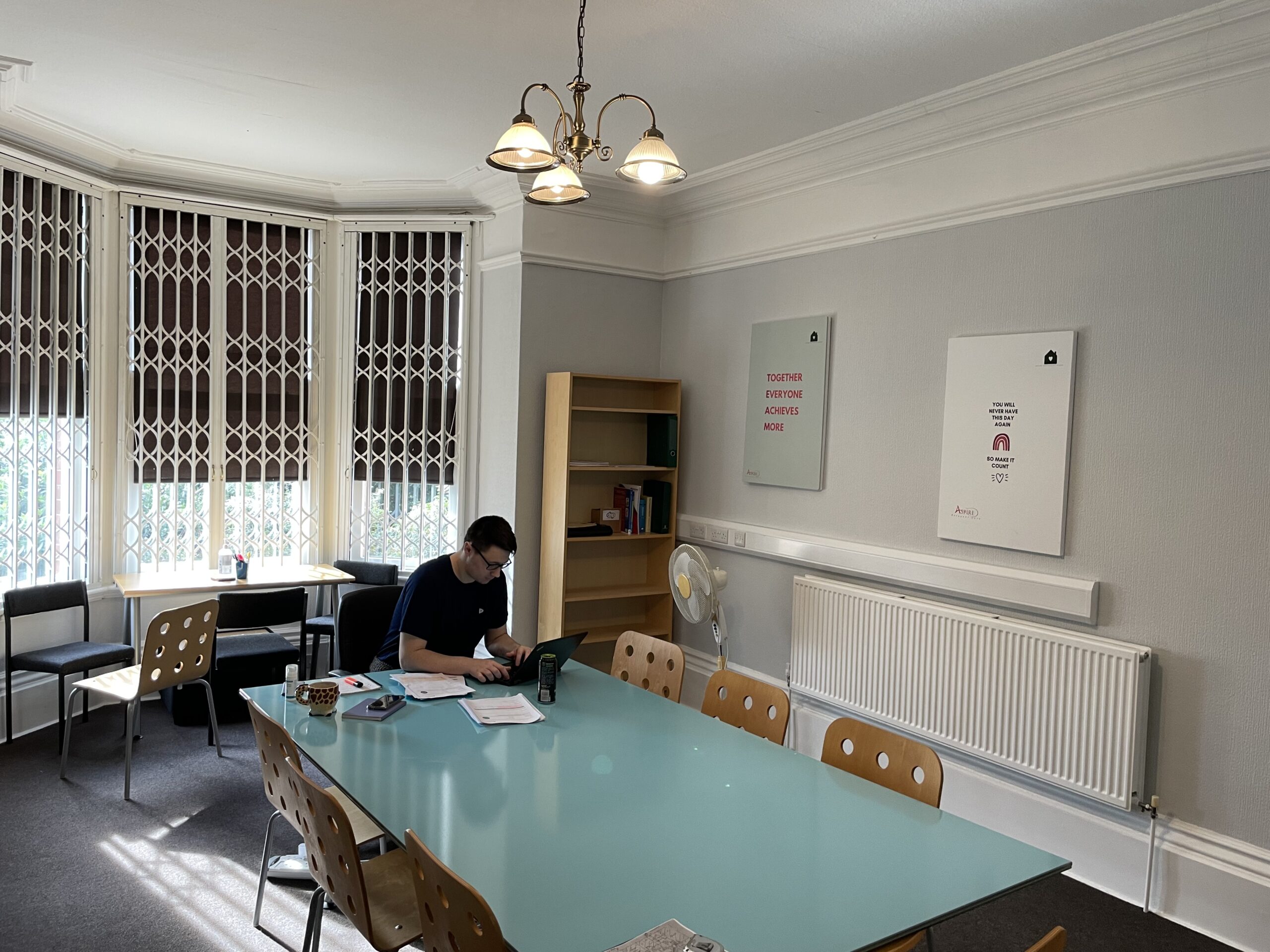 A meeting room at Aspire PC before the redesign, with a glass table and a bay window behind security grilles