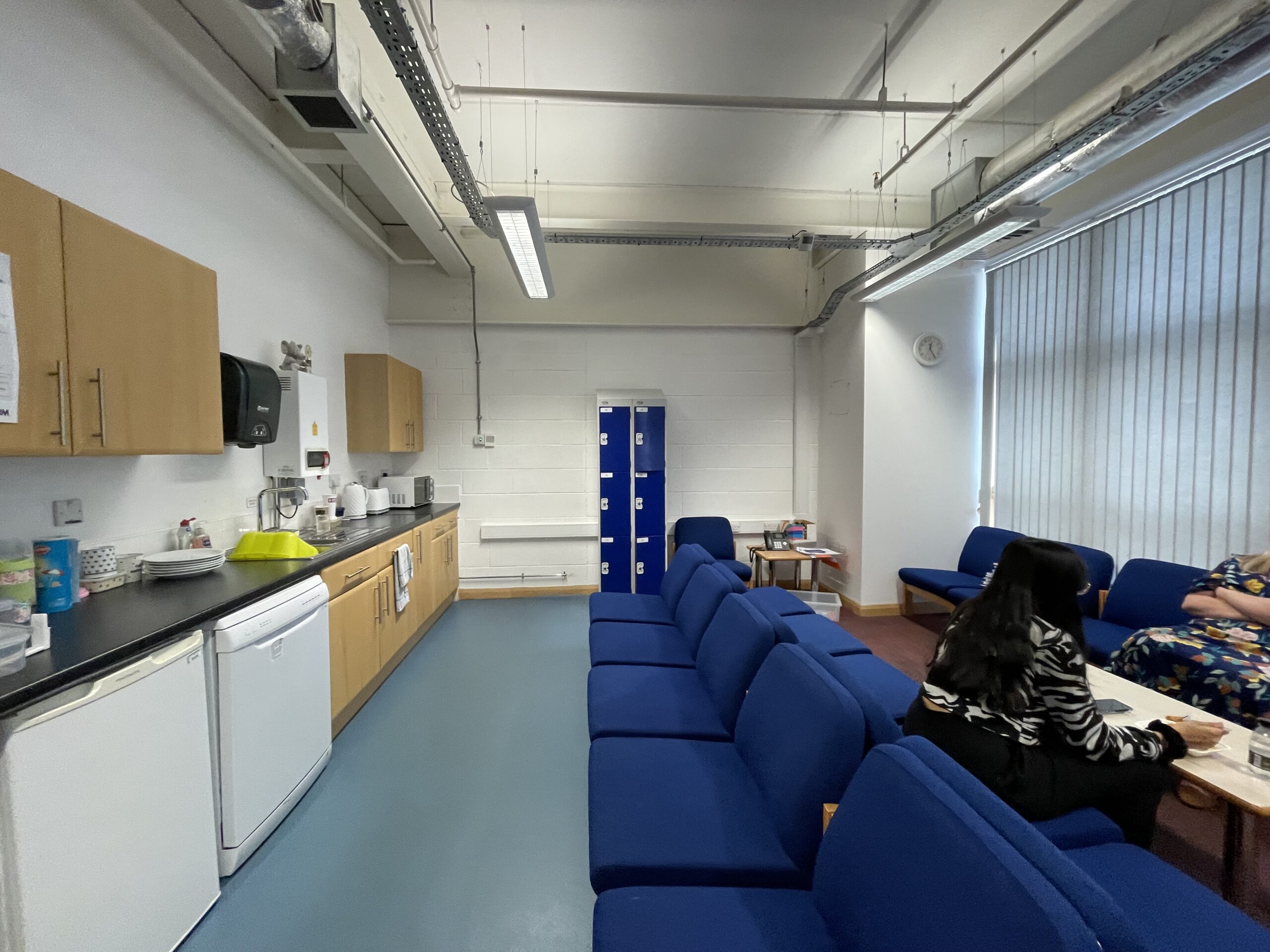 The staff room at the school before the refresh, with kitchen units, blue soft seating and lockers