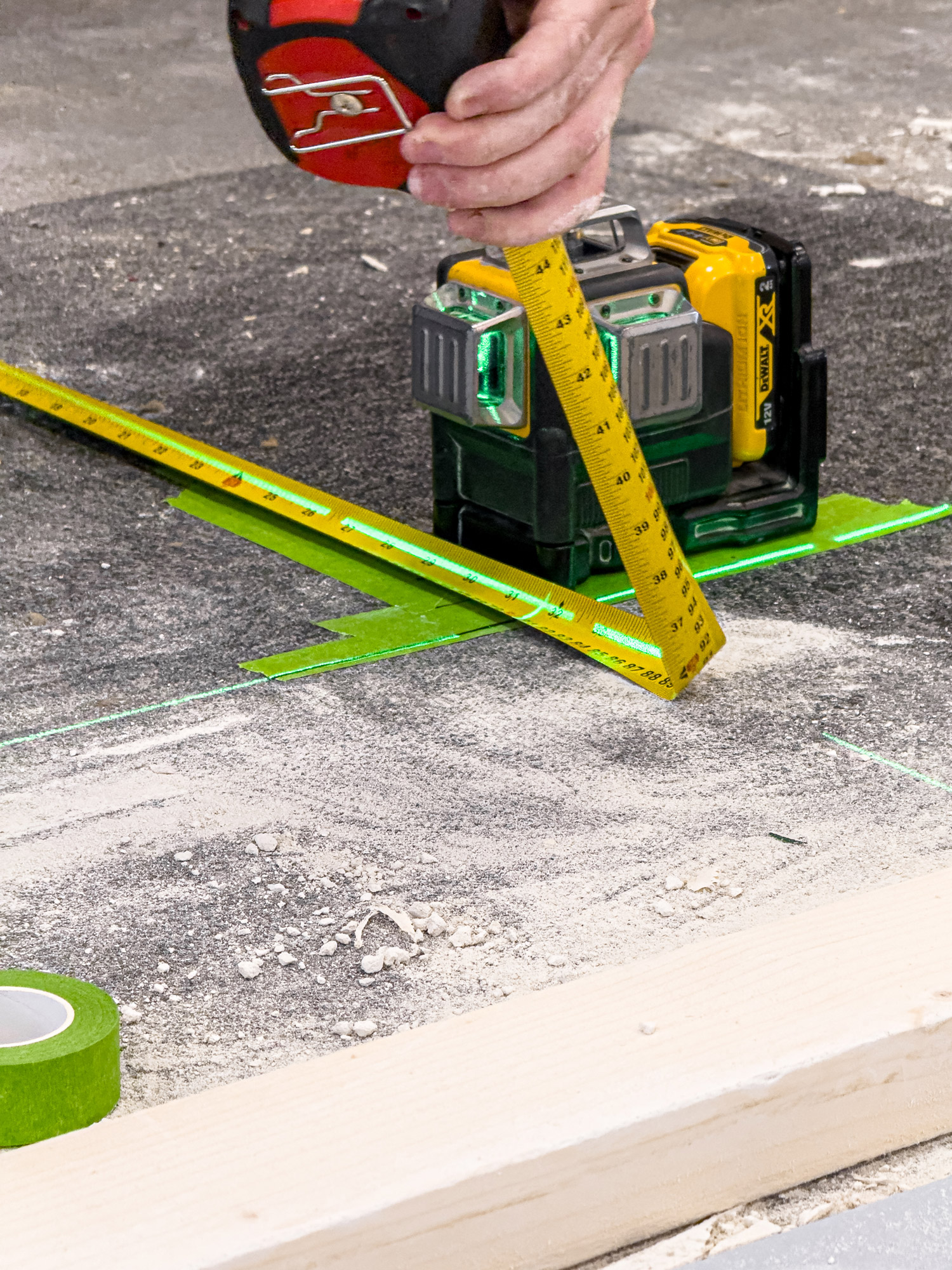 A laser level and tape measure set up on a concrete floor during a site survey