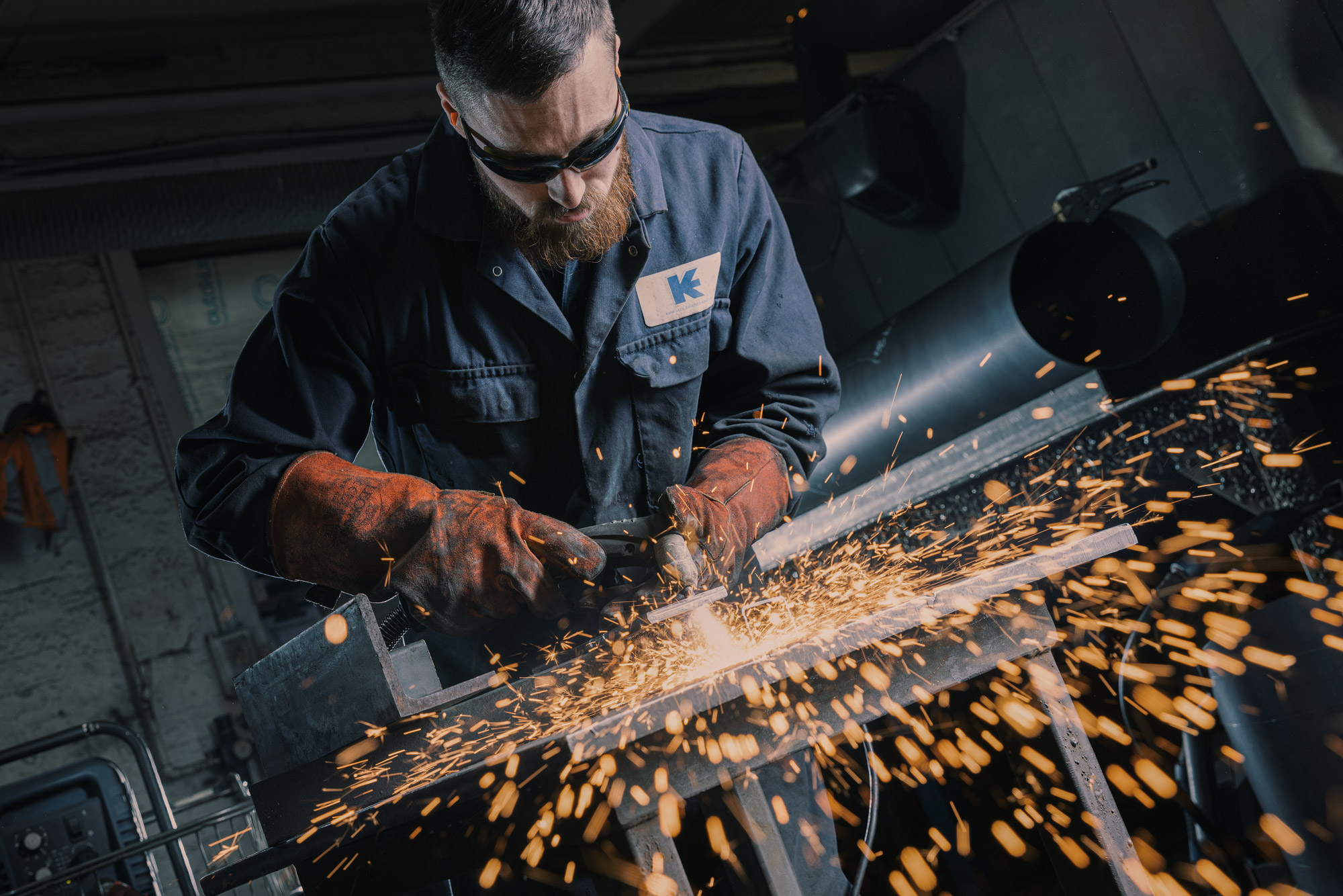 A welder grinding steel at Kirkgate Engineering, wearing a jacket carrying the Kirkgate mark