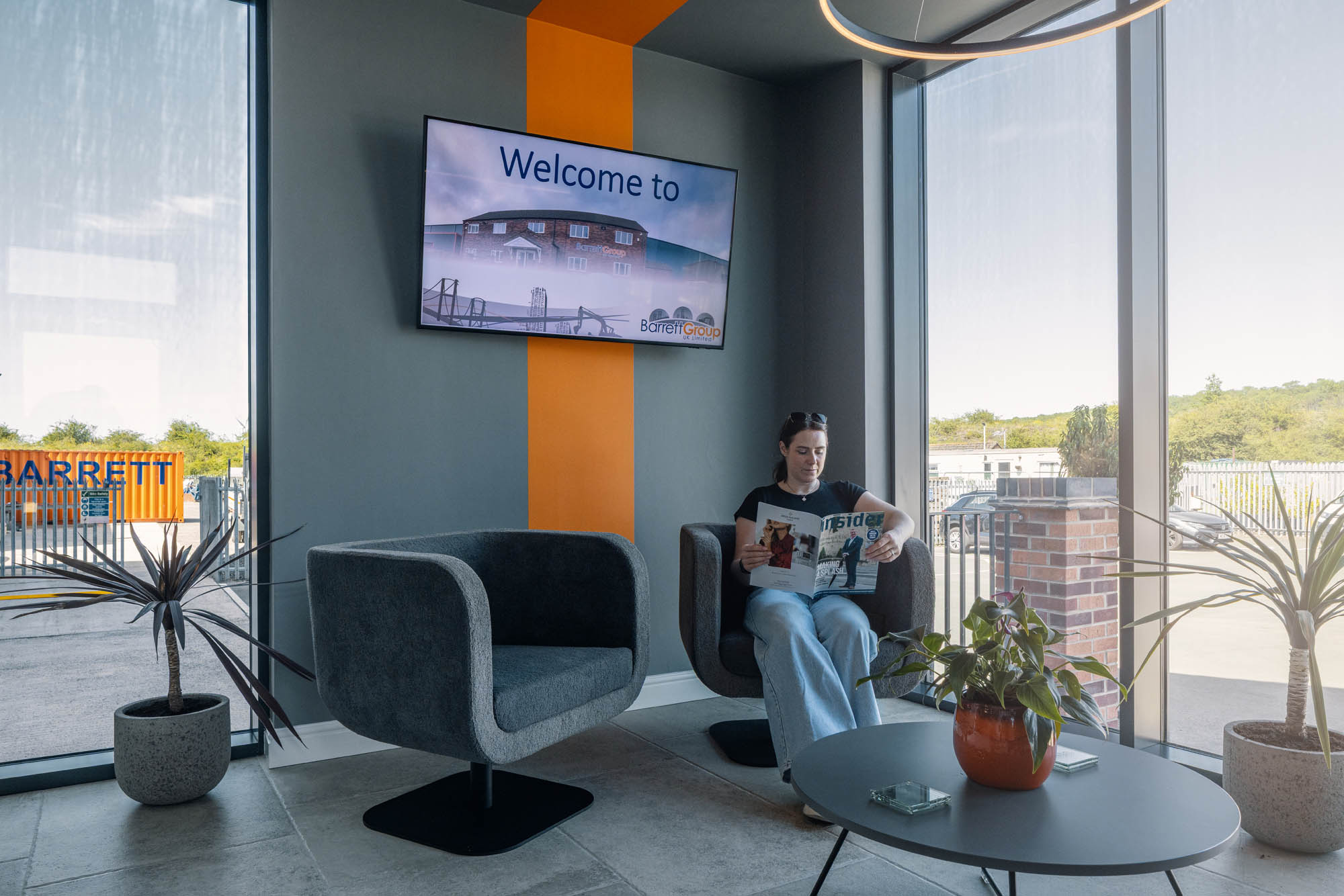 Reception seating at Barrett Group in Scunthorpe, with an orange feature stripe and a welcome screen