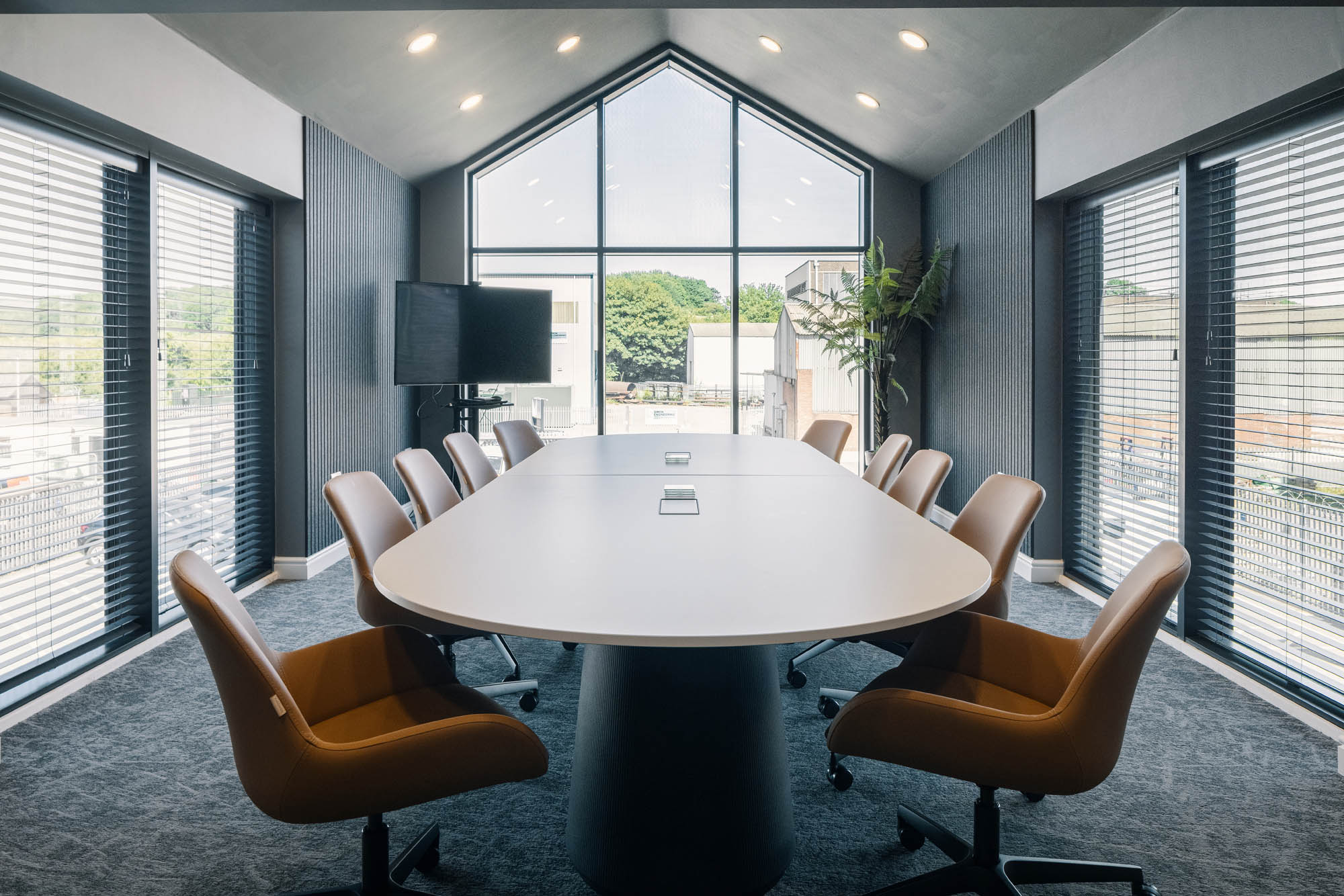 The boardroom, with a long meeting table, tan leather chairs and a full height gable window