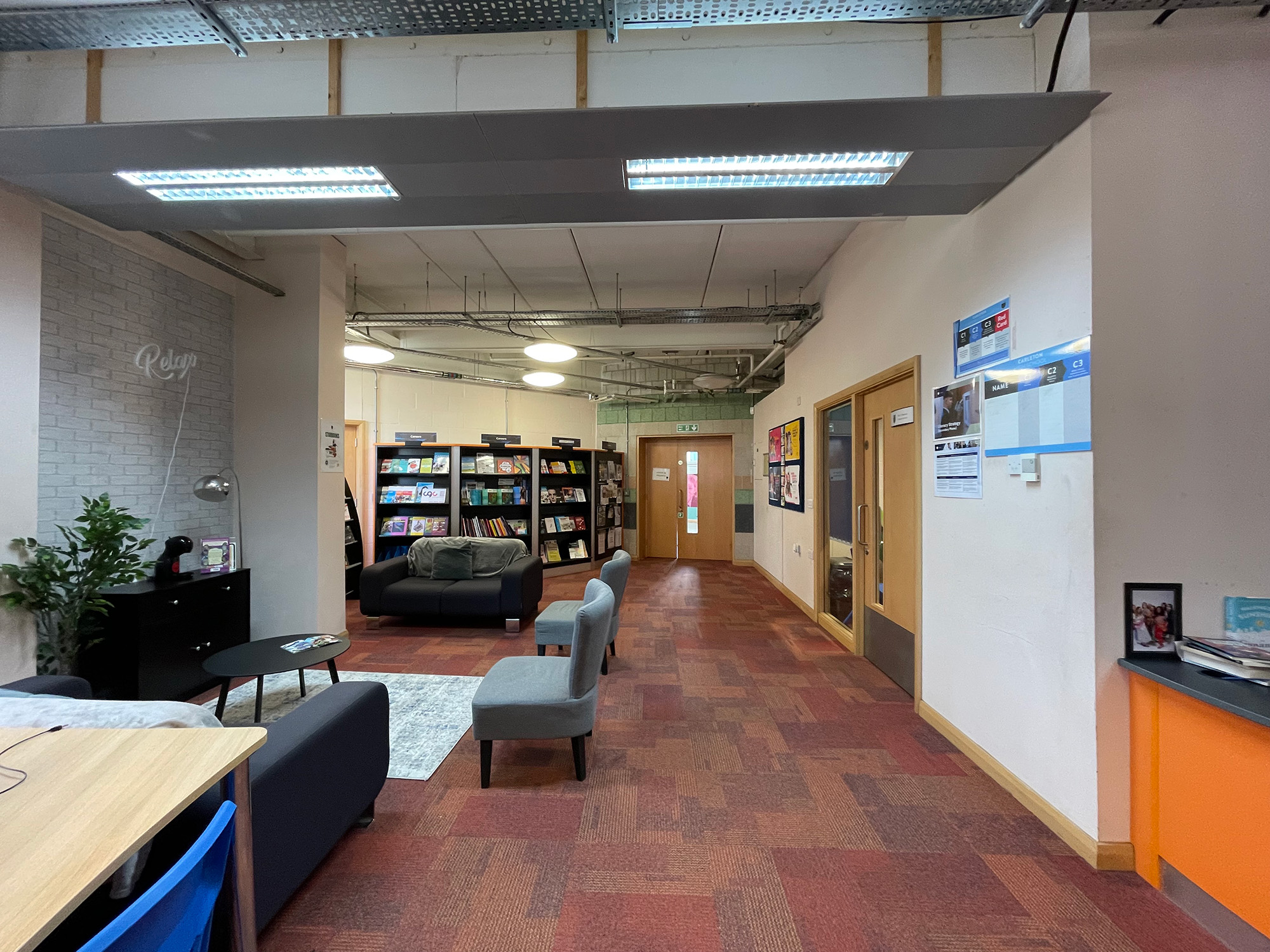 The original library entrance area before the redesign, with dark sofas, grey chairs and red carpet tiles