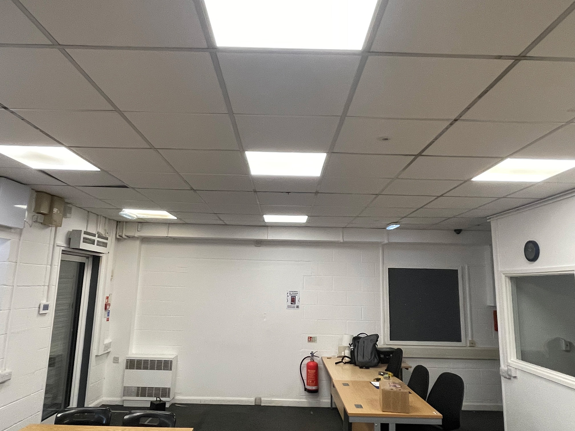 The original room before the redesign, with white painted blockwork, ceiling tiles and a single table in the corner